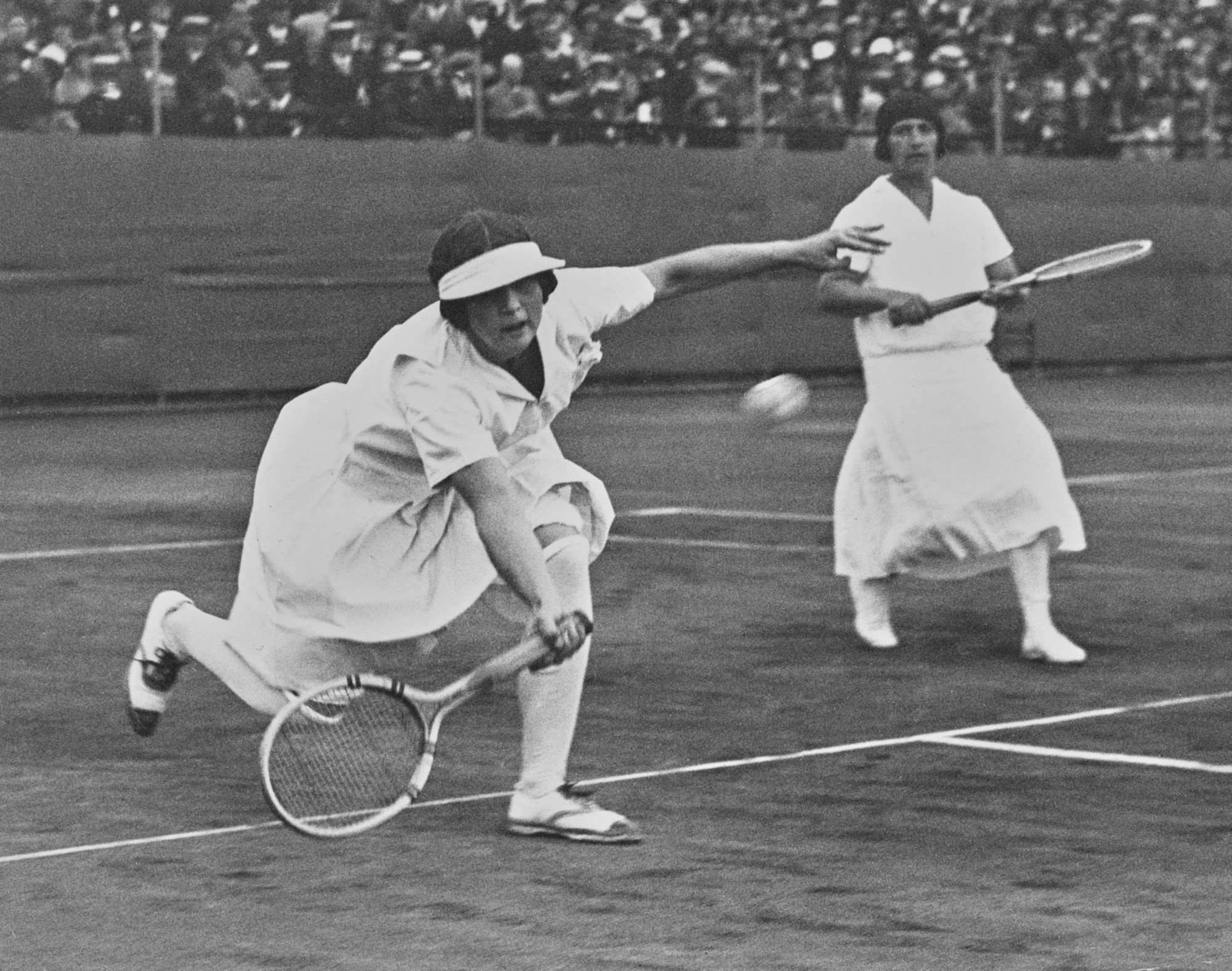 Helen Wills of the United States reaches to play a forehand return as compatriot partner Hazel Wightman looks on during their Women's Doubles Final in 1924