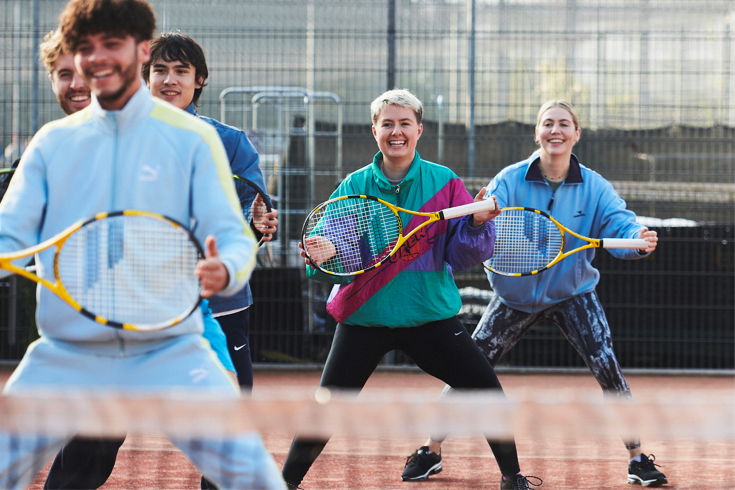 People smiling and holding tennis rackets