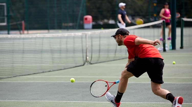 Club player reaching to hit a tennis ball on court
