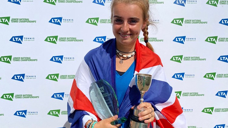 Female holding a trophy wrapped around in a flag