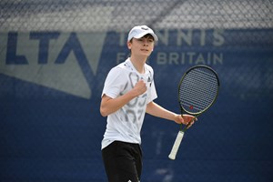 Charlie Robertson clenching his fist and holding his tennis racket at the 16U Junior Nationals