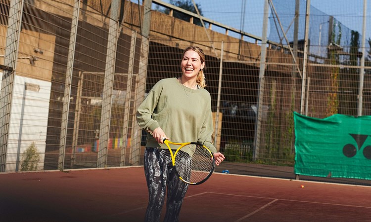 女子拿着球拍在网球场上大笑