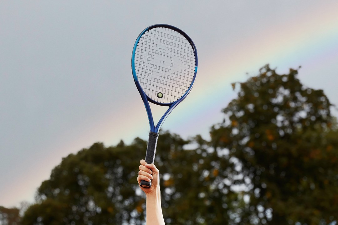 Tennis racket held up in front of rainbow