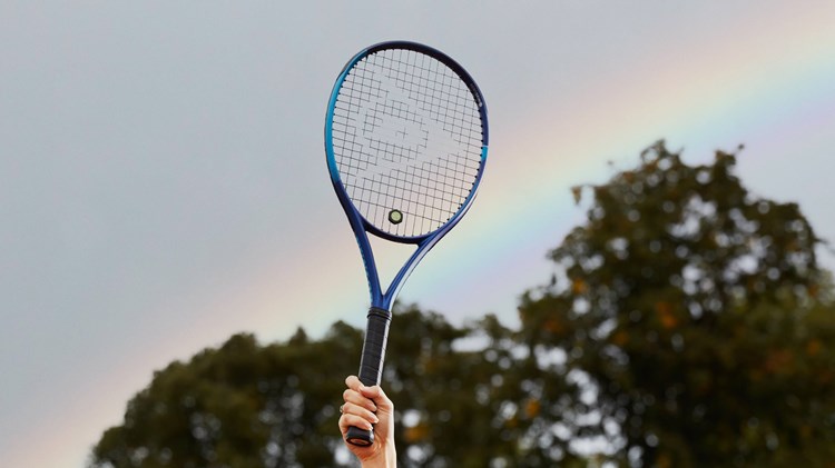 Tennis racket held up in front of rainbow