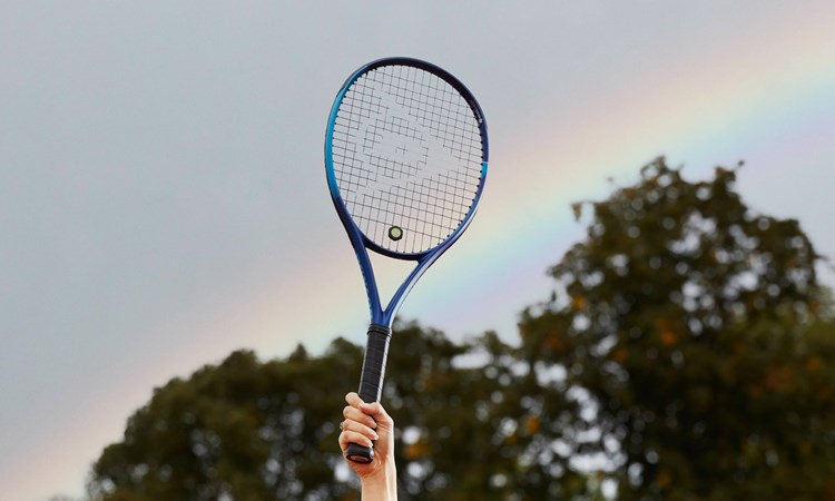 Tennis racket held up in front of rainbow