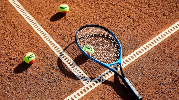 Close up of tennis racket and balls on clay court