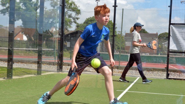 Young padel player returning a shot in a lesson