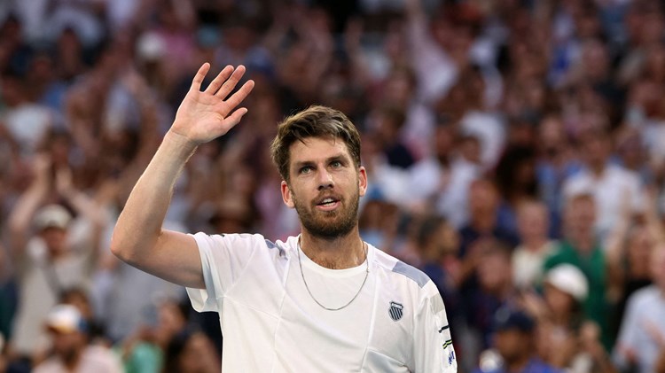 Cam Norrie smiling while holding his hand up in the air on court at the Australian Open