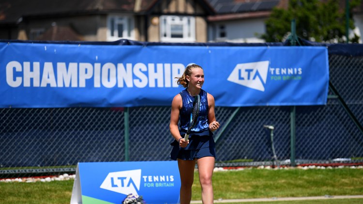 Player on court with blue LTA County Championships banner in background