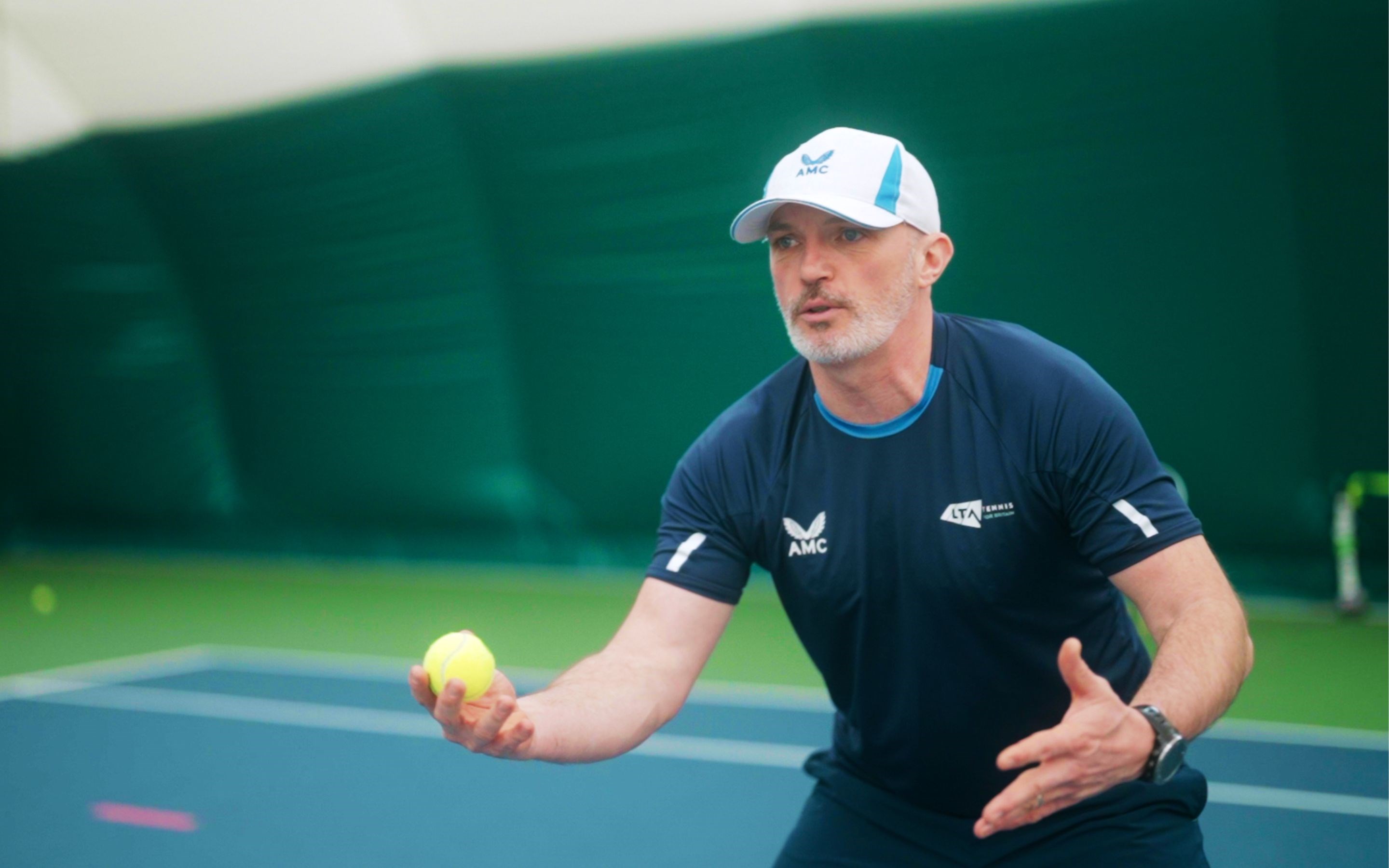 Coach, Shaun Dacon holding a tennis ball, during a session