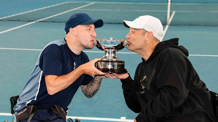 Andy Lapthorne and David Wagner kissing their quad doubles trophy on court at the Australian Open