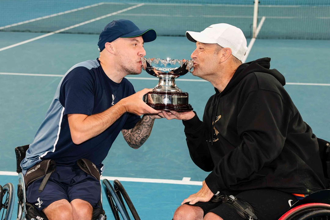 Andy Lapthorne and David Wagner kissing their quad doubles trophy on court at the Australian Open
