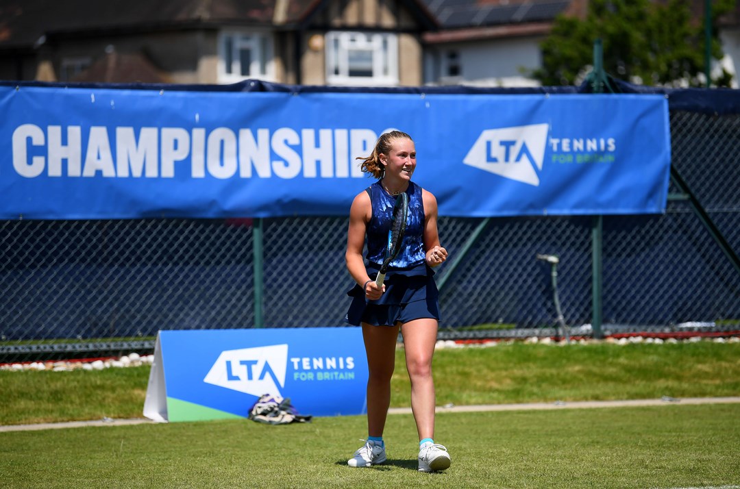 Player on court with blue LTA County Championships banner in background