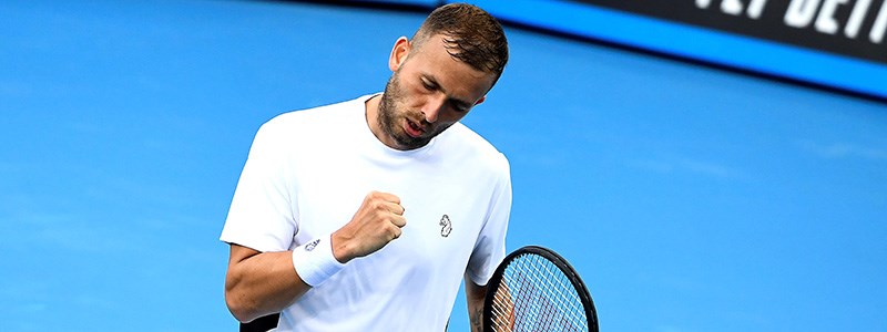 Dan Evans celebrating on a blue tennis court