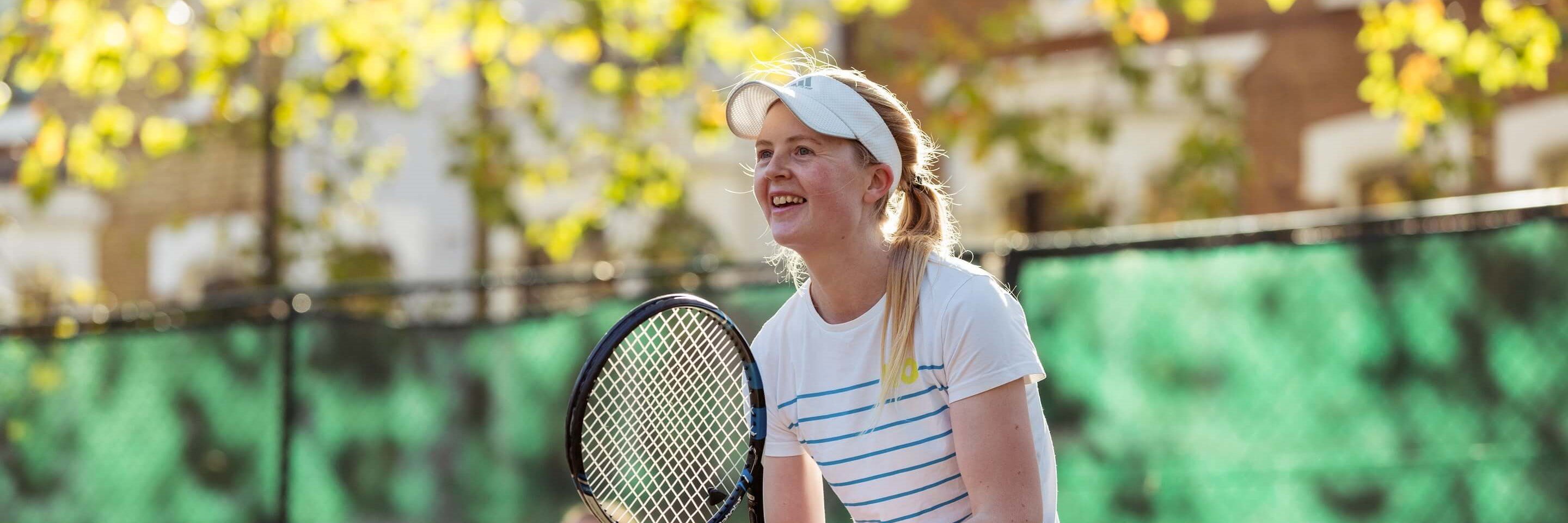 Woman on outdoor court getting ready to receive a shot