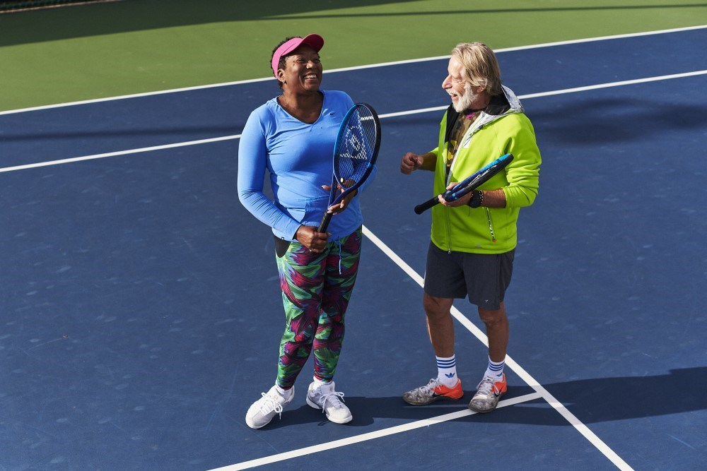 Two tennis players laughing together on court. 