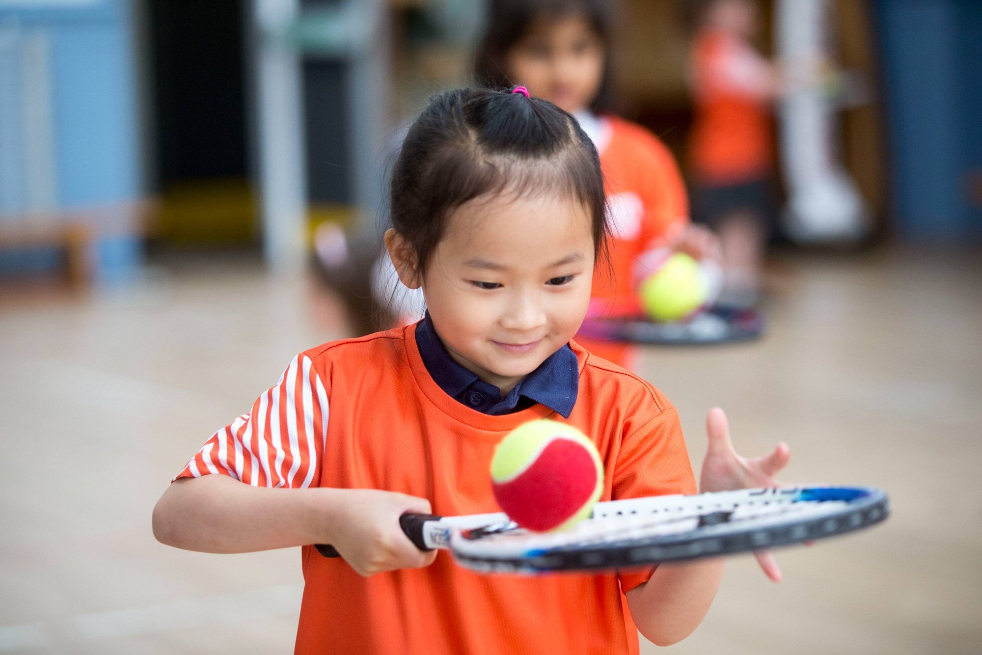Young girl balancing a tennis ball on a racket during an LTA Youth session