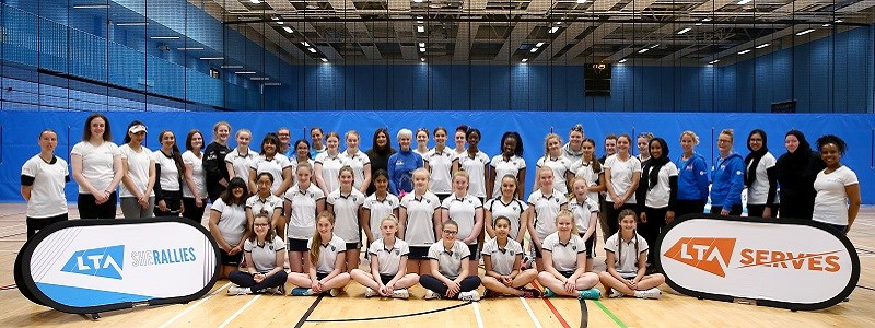 Judy Murray standing alongside girls tennis players smiling for a group picture with the LTA She Rallies banner