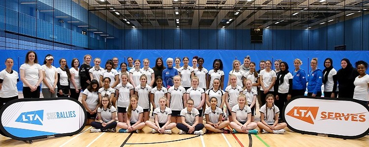 Judy Murray standing alongside girls tennis players smiling for a group picture with the LTA She Rallies banner