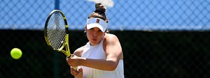 Eva Shaw playing a double backhand tennis shot at a tournament