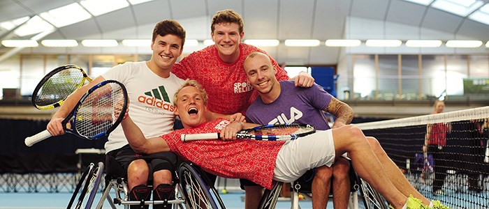 Jamie Laing laying across two wheelchair tennis players at the National Tennis Centre in London