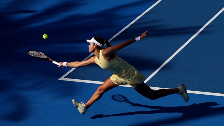 Emma Raducanu stretching to hit a backhand slice on court at the Qatar Open