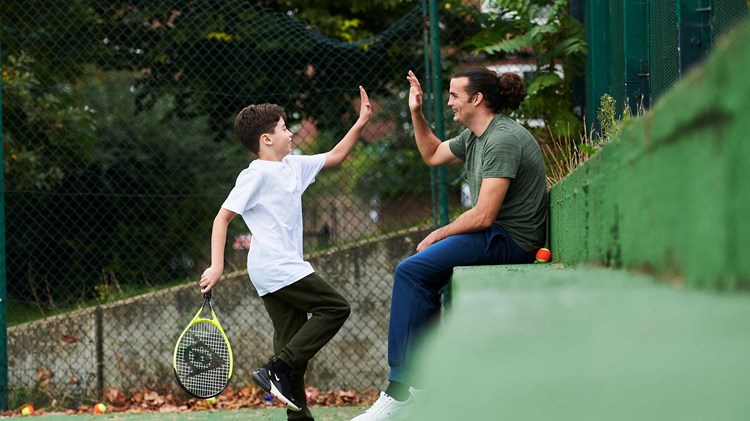 Young boy high fiving his dad watching on court