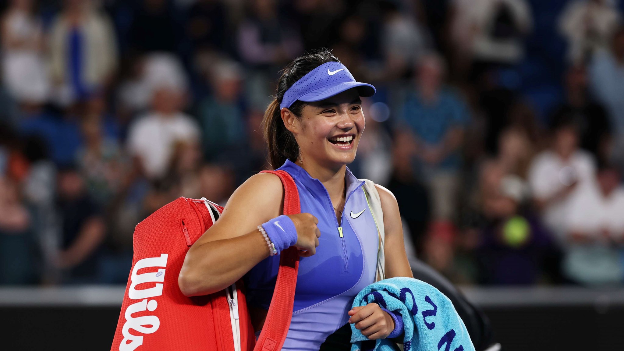 Emma Raducanu smiles walking out on court at the Australian Open