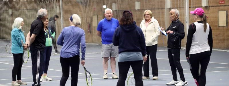 A group of people on court taking part in the Tennis4RAd 10-week pilot course of tennis-based fitness classes. 
