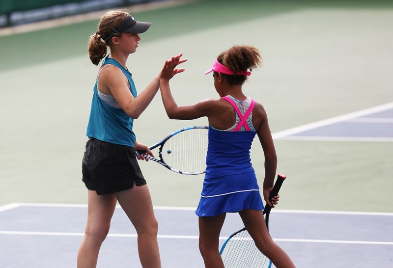 Girls doubles pair high fiving