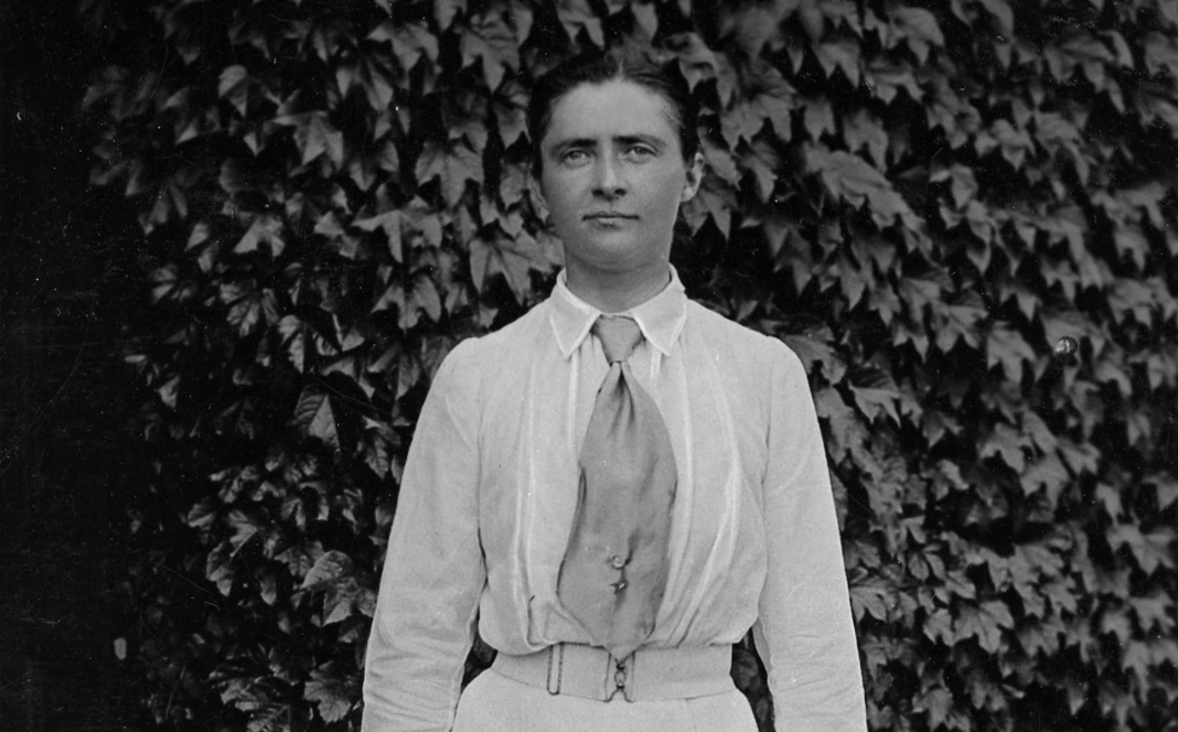 A black and white photo of Toupie Lowther stood in front of plants