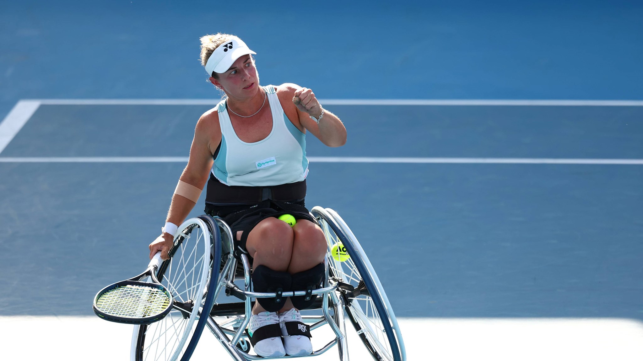 Wheelchair tennis star Lucy Shuker clenching her fist on court while holding her tennis racket