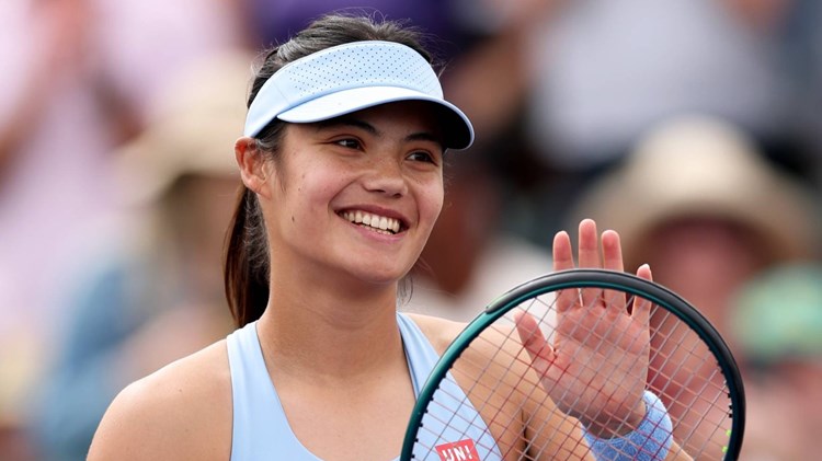 Emma Raducanu smiling while clapping her tennis racket on court at the BNP Paribas Open Indian Wells