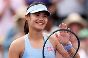 Emma Raducanu smiling while clapping her tennis racket on court at the BNP Paribas Open Indian Wells