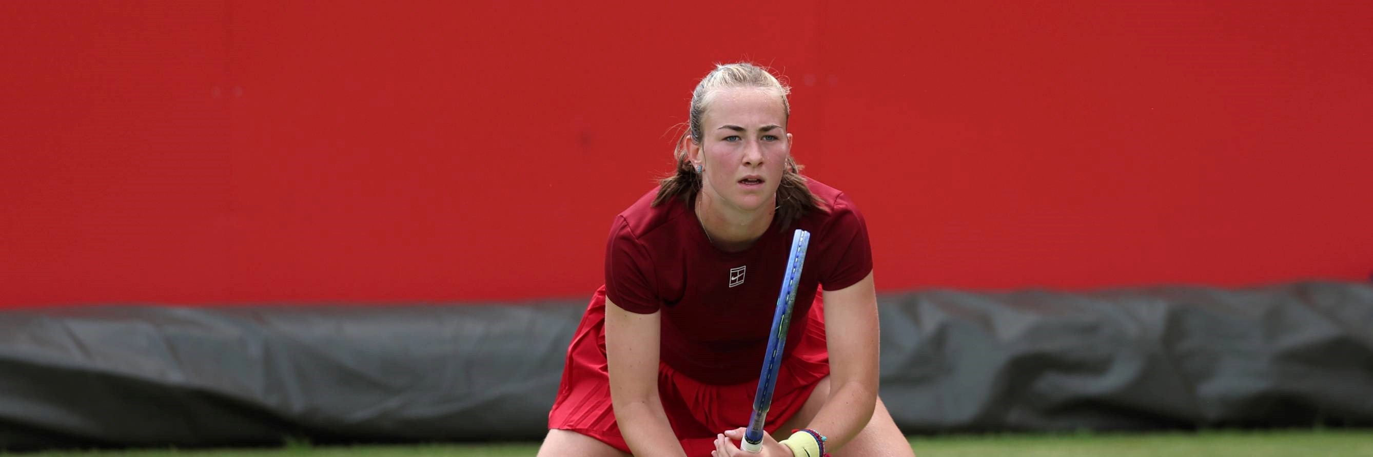 British tennis player Mika Stojsavljevic stood on a grass court while preparing to hit a return