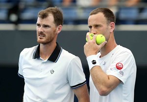 Jamie Murray and doubles partner Michael Venus holding two tennis balls and whispering to each other