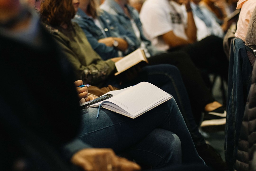 An image of a person taking notes at a meeting