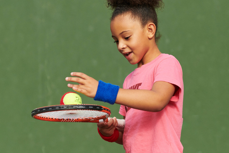 Young girl balancing a tennis ball on a racket as part of an LTA Youth Start tennis programme