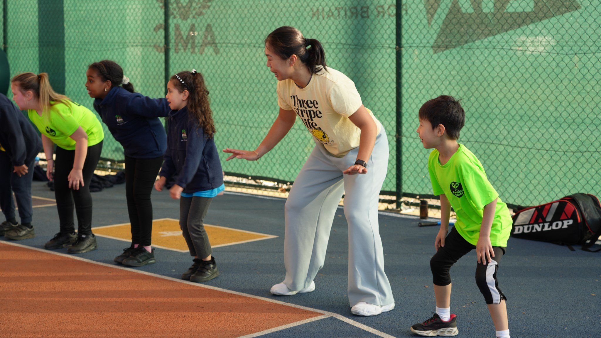 4 young people are stood in the ready position on the baseline of a court