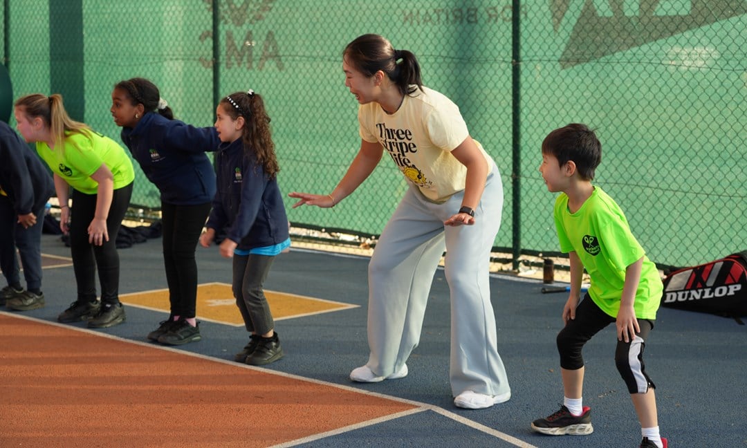 4 young people are stood in the ready position on the baseline of a court