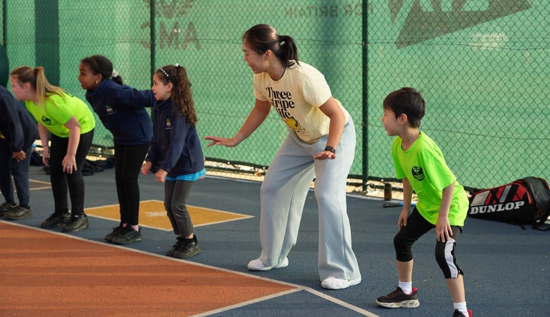 4 young people are stood in the ready position on the baseline of a court