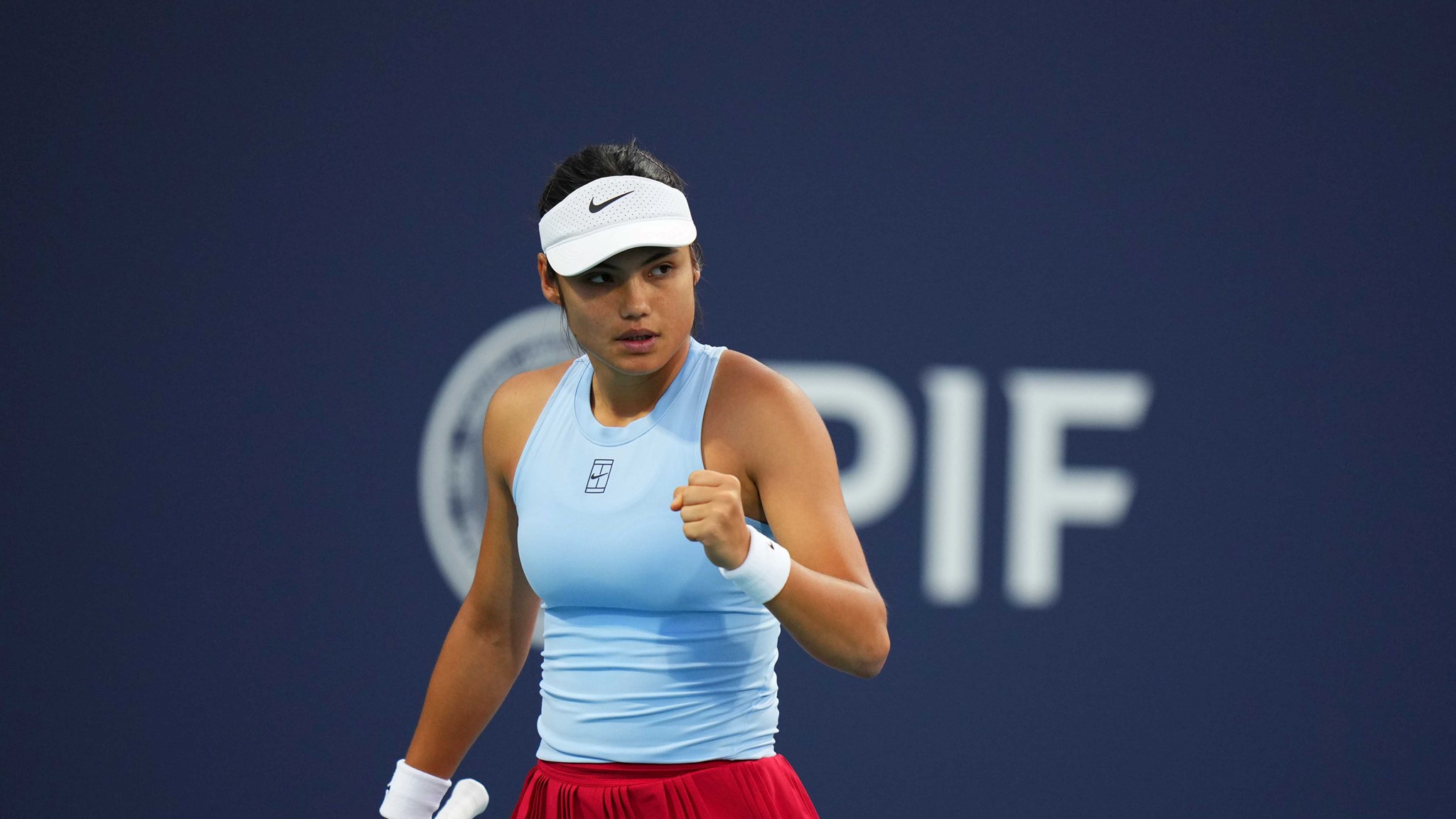 Emma Raducanu wearing a blue Nike top while clenching her fist on court at the Miami Open