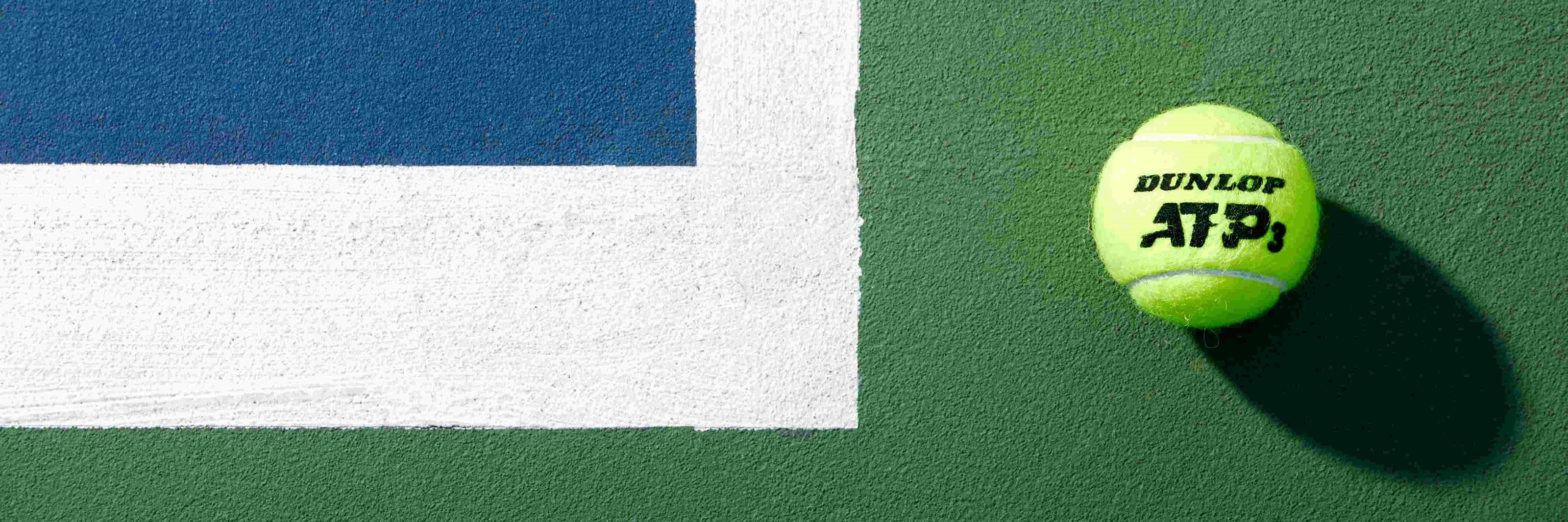 Dunlop tennis ball by the baseline