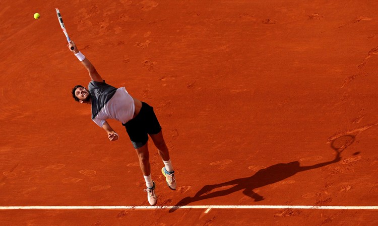 Cam Norrie stretching to his a serve on a clay court at the Monte Carlo Masters