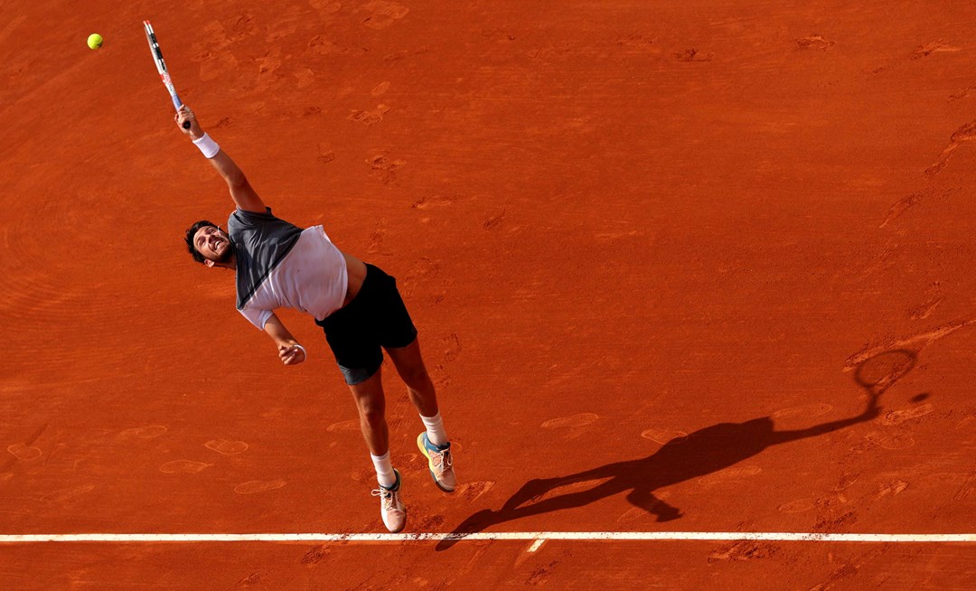 Cam Norrie stretching to his a serve on a clay court at the Monte Carlo Masters