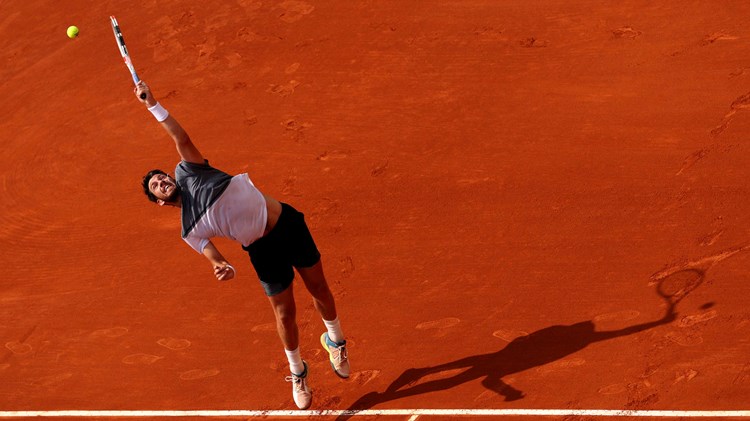 Cam Norrie stretching to his a serve on a clay court at the Monte Carlo Masters