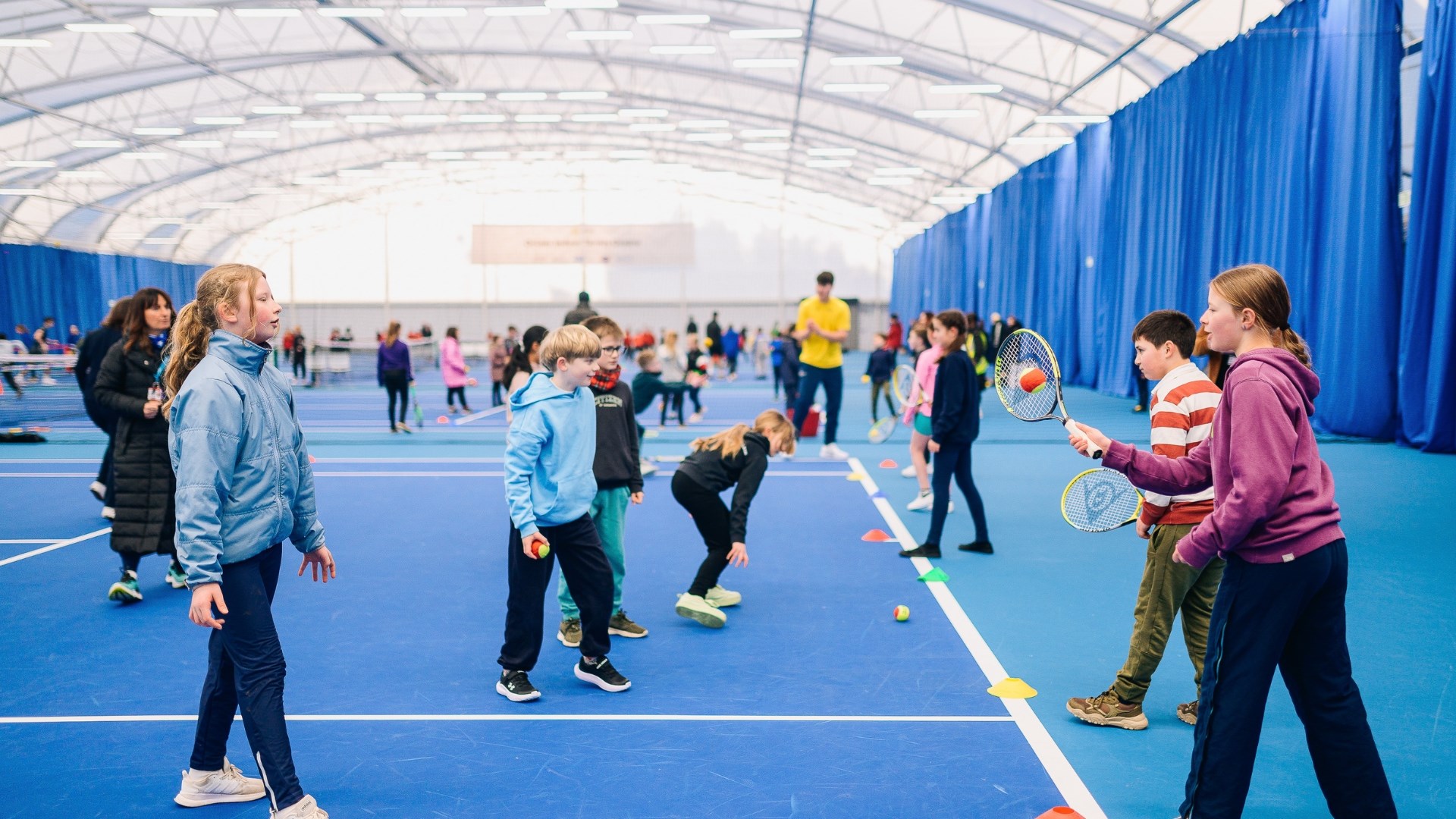 children practicing hitting a ball with a racket