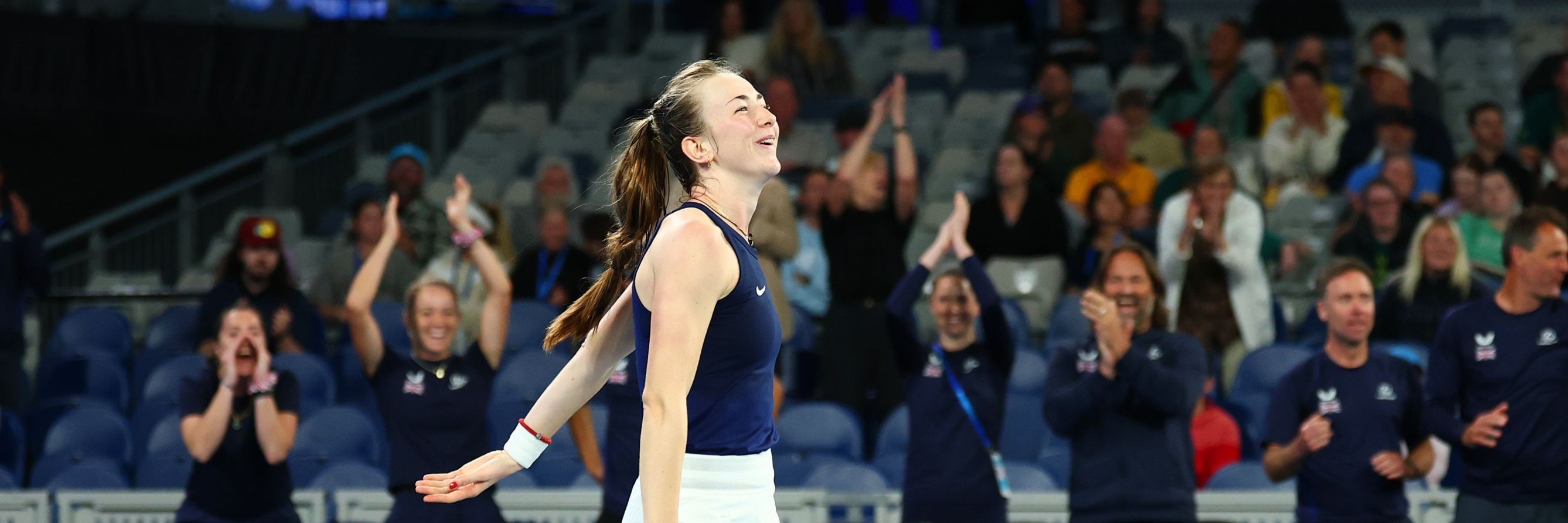 Mika Stojsavljevic smiling on court while holding her tennis racket after winning her first Billie Jean King Cup match on debut