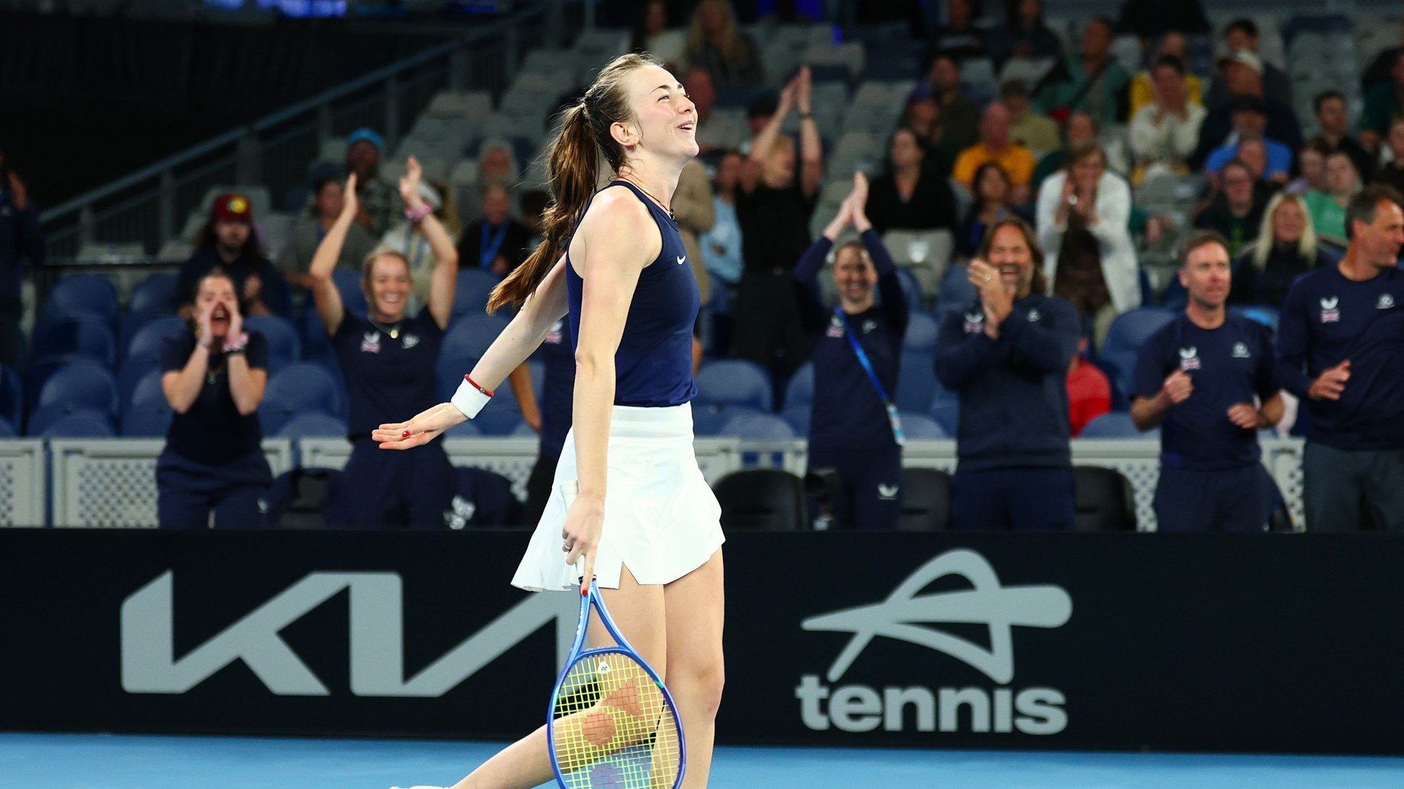 Mika Stojsavljevic smiling on court while holding her tennis racket after winning her first Billie Jean King Cup match on debut