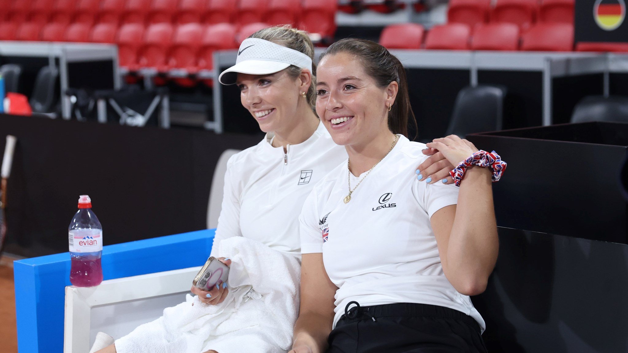 Katie Boulter and Jodie Burrage sat down, smiling and holding hands at the Billie Jean King Cup Qualifiers